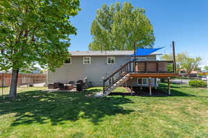 Rear view of house featuring fence, an outdoor fire pit, a wooden deck, stairway, and a yard