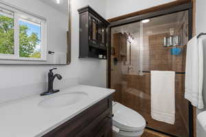 Primary suite bathroom with vanity, a shower stall, and toilet