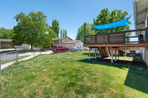 View of yard featuring fence, a wooden deck, and stairs