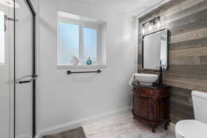 Bathroom featuring wood walls, vanity, and toilet