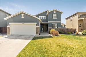Craftsman-style home featuring fence, stucco siding, an attached garage, and stone siding