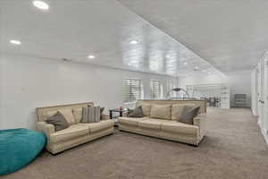 Carpeted living area featuring recessed lighting, a textured ceiling, and visible vents