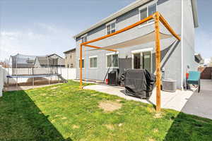 Rear view of house with a fenced backyard, a trampoline, and a patio area