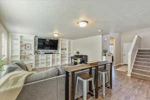 Living area featuring baseboards, a textured ceiling, stairs, and wood finished floors