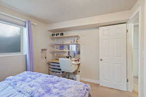 Carpeted bedroom featuring a textured ceiling and baseboards