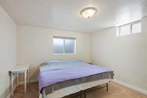 Carpeted bedroom featuring baseboards and a textured ceiling