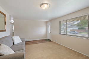 Unfurnished living room featuring baseboards, carpet flooring, a textured ceiling, and visible vents