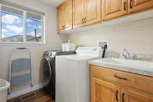 Laundry area with dark wood-style flooring, visible vents, washing machine and dryer, cabinet space, and a sink
