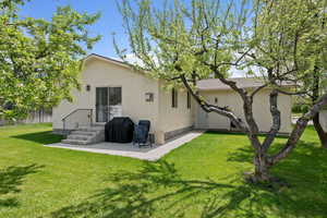 Back of house featuring stucco siding and a yard