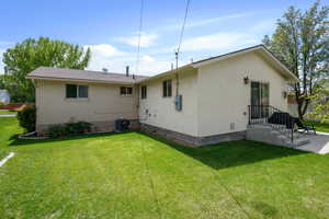 Back of house with central AC unit, stucco siding, a yard, and brick siding