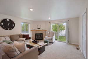 Living area with baseboards, a fireplace, light colored carpet, and visible vents