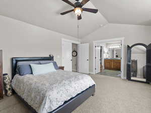 Bedroom featuring vaulted ceiling, baseboards, light colored carpet, ceiling fan, and ensuite bathroom