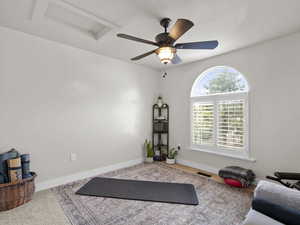 Exercise room featuring visible vents, carpet floors, baseboards, attic access, and ceiling fan