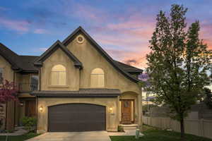 View of front of property featuring fence, driveway, and stucco siding