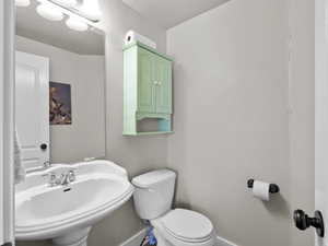 Half bathroom featuring toilet, a sink, and baseboards