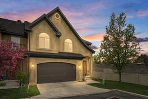 View of front of property featuring concrete driveway, fence, a garage, a lawn, and stucco siding