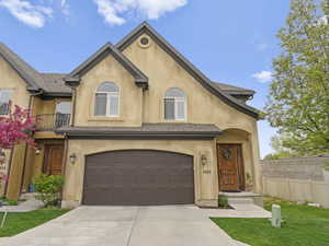 View of front facade featuring concrete driveway, fence, a garage, and stucco siding