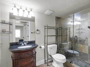 Bathroom with baseboards, a shower stall, toilet, and vanity