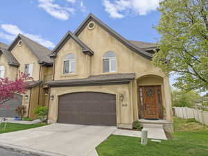 View of front of home with a garage, driveway, fence, a front yard, and stucco siding