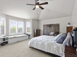 Bedroom with ceiling fan, vaulted ceiling, multiple windows, and carpet