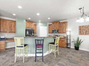 Kitchen featuring a kitchen breakfast bar, stainless steel microwave, black refrigerator with ice dispenser, a kitchen island, and baseboards
