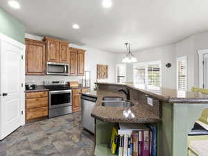 Kitchen with a sink, recessed lighting, an inviting chandelier, an island with sink, and appliances with stainless steel finishes