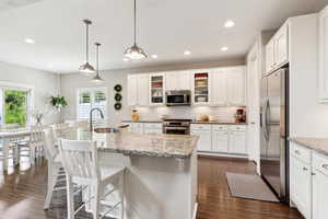 Kitchen featuring dark wood-type flooring, white cabinetry, tasteful backsplash, a sink, and appliances with stainless steel finishes