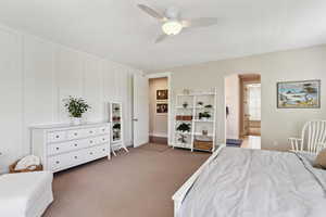 Carpeted bedroom featuring arched walkways, ceiling fan, ensuite bathroom, and a decorative wall