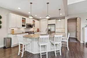 Kitchen with appliances with stainless steel finishes, a sink, arched walkways, white cabinetry, and backsplash