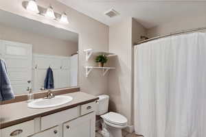 Full bathroom with visible vents, tile patterned flooring, curtained shower, vanity, and toilet