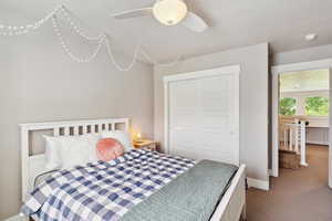 Carpeted bedroom with baseboards, ceiling fan, and a closet