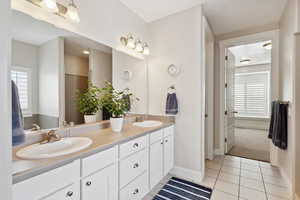 Full bathroom with double vanity, baseboards, a sink, and tile patterned flooring