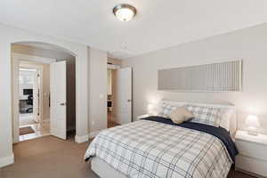 Carpeted bedroom featuring arched walkways and baseboards