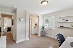 Office area featuring light colored carpet, arched walkways, and baseboards