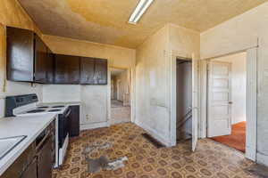 Kitchen featuring light countertops, dark brown cabinetry, visible vents, and range with electric stovetop