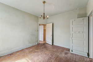 Spare room with baseboards, a notable chandelier, and wood finished floors