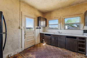 Kitchen with a sink, dark floors, dark brown cabinets, and light countertops