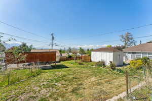 View of yard featuring an outdoor structure, a shed, and fence