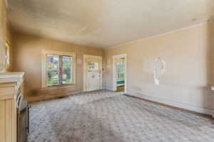 Unfurnished living room featuring carpet flooring, a textured ceiling, and a healthy amount of sunlight