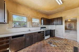 Kitchen featuring a sink, dark brown cabinets, white range with electric cooktop, and light countertops