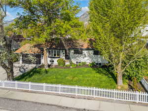 View of front facade featuring a fenced front yard, a mountain view, a front lawn, concrete driveway, and an attached garage