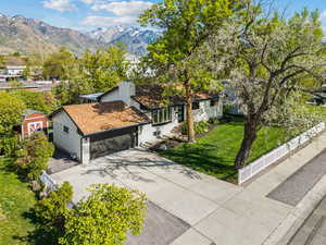 View of front of property featuring roof with shingles, a front yard, fence private yard, a garage, and concrete driveway
