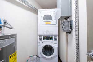 Washroom featuring laundry area, stacked washer and dryer, and electric water heater