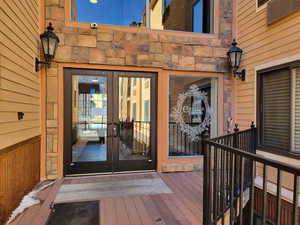 View of exterior entry featuring a deck, french doors, and stone siding
