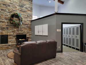 Living area with a high ceiling, a fireplace, baseboards, wood finished floors, and beamed ceiling