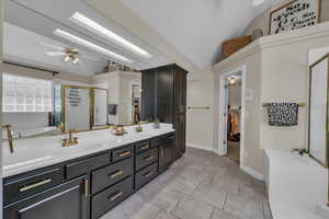 Bathroom featuring a sink, ceiling fan, a stall shower, and lofted ceiling