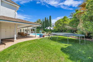 View of yard featuring a patio area, a trampoline, and an outdoor pool