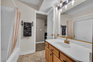 Full bath featuring baseboards, shower / bathtub combination with curtain, and vanity