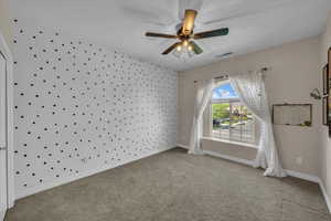 Carpeted empty room featuring a ceiling fan, baseboards, and visible vents