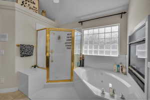 Bathroom with a tub with jets, tile patterned flooring, and a stall shower